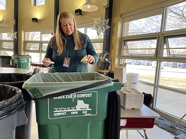 Woman throws compostable soup cup into Black Earth compost bin